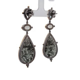 Pair of earrings with teardrop-shaped black stones on a white background